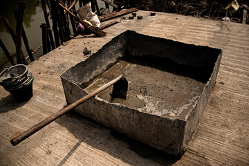 Fototapeta na wymiar basin, hoe, concrete, worker, employee, cement in a large basin. Jungle, Asia, broom