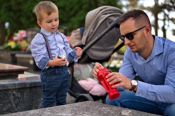 Father and son lighting a candle at the grave