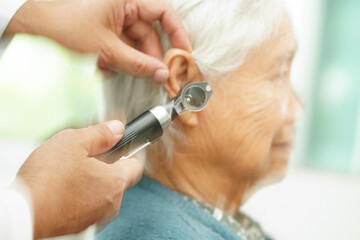 Otolaryngologist or ENT physician doctor examining senior patient ear with otoscope, hearing loss...