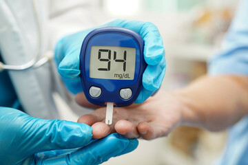 Asian doctor using digital glucose meter for check sample blood sugar level to treatment diabetes.