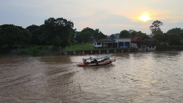 Tugboat sailing in Chao Phraya River at sunset in Ayutthaya, Thailand