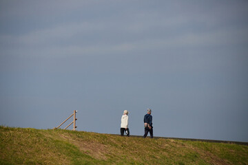 秋の海岸の堤防で散歩しているシニア夫婦の姿