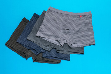 A set of four men's multi-colored underpants on a blue background.