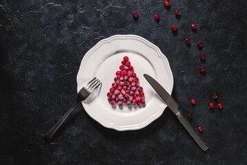 Table setting with Christmas decor. Symbol Christmas tree from a frozen red berries on the white...