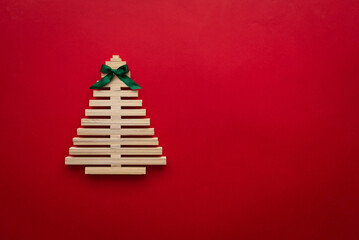 symbol Christmas tree from a wooden sticks on red background. Empty copy space for your greetings