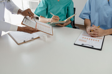 A group of doctors is brainstorming together in a conference room, There was a meeting about major surgery in the hospital, The doctor takes the patient's documents and discusses them with team.