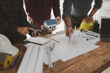 Architects and engineers work together to come up with solutions to house building problems, The property is about to be designed by a group of engineers, Architects are reviewing plans together.