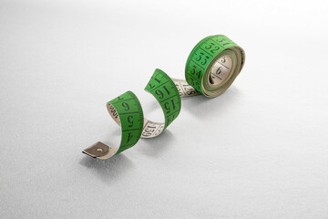 Close-up of a green spiral tape measure on a white background