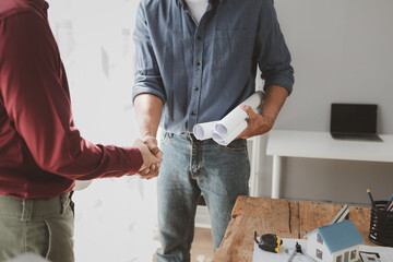 The architect shake hands with the foreman as the job was agreed upon, An engineer contracts with a company to construct a building, Engineer and architect check hand as work is finalized.