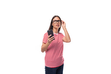 Obraz na płótnie Canvas charming young caucasian woman with straight hair with glasses and in a striped t-shirt holds a smartphone in her hand. people lifestyle concept