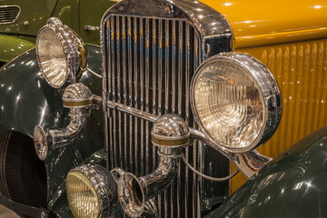 Detail of the headlight and radiator of a classic car.
