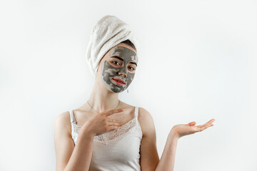 Beautiful young woman with black clay facial mask for perfect fresh clean skin isolated on white....