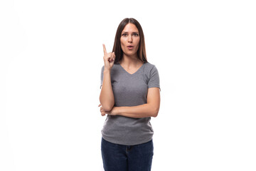 young pretty brunette woman in a gray corporate color t-shirt on a white background with copy space