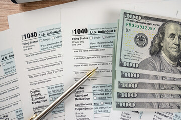 Dollar bills and pen lying on the 1040 form. The concept of filing a tax return - obrazy, fototapety, plakaty