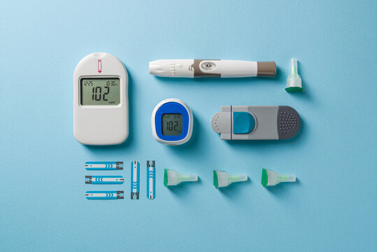 Top view of glucometer, lancet pen and strips on blue background. diabetes test kit