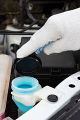 the driver pours fluid into the washer reservoir.
