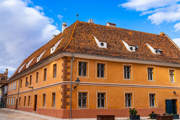 A large yellow building with a brown roof. A Majestic Yellow Building With a Rustic Brown Roof