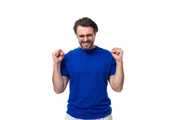young brunette European man with a well-groomed beard in a blue T-shirt hopes for the best
