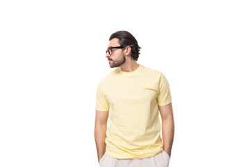 Fototapeta premium attractive young brunette man with a beard in a yellow t-shirt wears eyeglasses