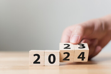 New year 2023 change to 2024. Hand flip over wooden cube block. New year resolution goal concept