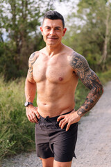 portrait looking at camera of a sportsman with fitness body smiling in the countryside, concept of sport in nature and active lifestyle, copy space for text