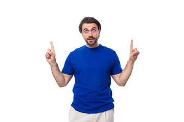 Fototapeta premium young brutal caucasian brunette man with a beard in a blue t-shirt keeps the secret of business development on a white background with copy space