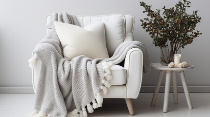 A cozy light soft chair with soft knitted blanket and coffee table with vase on the background of a gray plaster wall