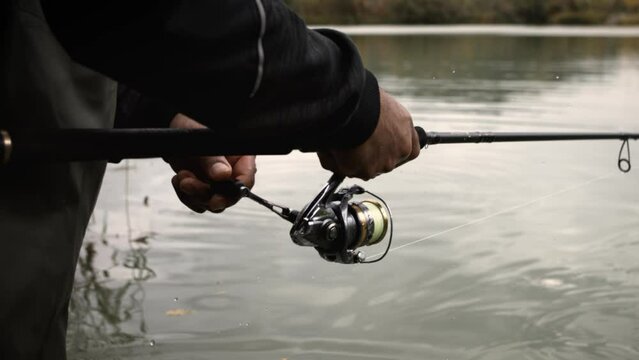 Close Up Fisherman Winding Reel Reeling In Fishing Rod super slow motion
