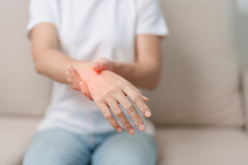 Woman having wrist pain during sitting on sofa at home, muscle ache due to De Quervain s...