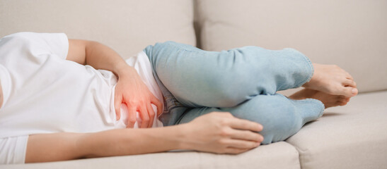 woman having abdomen ache due to Stomach pain, digestion with constipation or Diarrhea from food poisoning, female problem and Endometriosis, Hysterectomy and Menstrual on the sofa at home