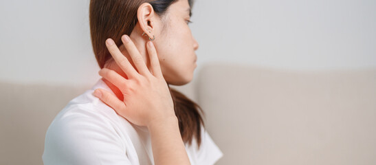 Woman having Neck and Shoulder pain during sitting on couch at home. Muscle painful due to...