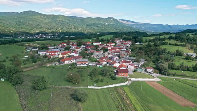 A small old village in the middle of a hill with high hills in the background. Drone footage, Slovenia