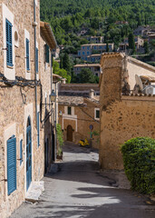 Stunning cityscape of the small coastal village of Deia in Mallorca, Spain. Traditional houses, narrow street, at the end of the street there is a yellow scooter.Tourist destinations in Spain.