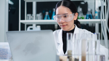 A female geologist or archaeologist is with laptop to check rock or mineral sample in paleontology,...