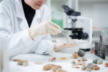 Close up of geologist or archaeologist is picking and focusing on a sample of rock, stone or...