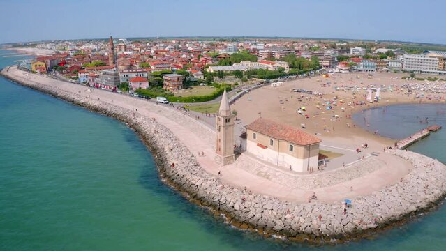 4k drone forward video (Ultra High Definition) of Madonna dell'Angelo church - small chapel and pilgrimage destination, built in 1751 and dedicated to the Virgin Mary. Bright Caorle cityscape, Italy.