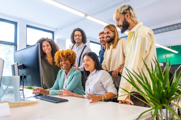 Coworkers using computer together and smiling looking the screen