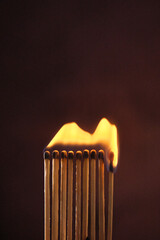 a row of matches are lit on a dark background