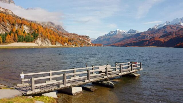 4k drone forward video (Ultra High Definition) of wooden pier on Sils Lake (Silsersee). Amazing autumn scene of Swiss Alps, Maloja Region, Upper Engadine, Switzerpand, Europe..