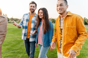 Group of multiethnic smiling friends wearing colorful clothes, meeting, talking, on the street