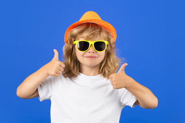 Kid boy making thumbs up sign. Fashion portrait of kid in summer hat, t-shirt and sunglasses on...