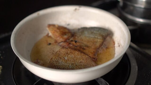 Frying milkfish in oil over a white pan