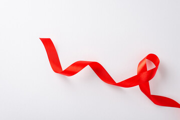 HIV Awareness Month idea: Top view of a red ribbon on a blank white surface with space for your message