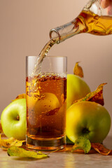 Apple cider is poured from a bottle into a glass.