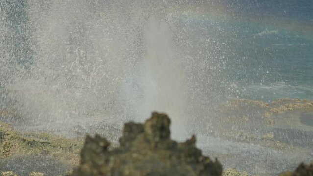 Close up shot of blow hole in Tinian, Northern Mariana Island with a rainbow showing