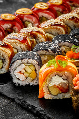Set of different sushi rolls on a black board. Assorted Japanese sushi with salmon, eel, shrimp
