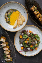 Pumpkin salad and soup, shrimp and marinated cheese canapes on dark background top view, flat lay