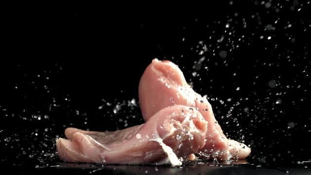 Chicken meat falls on a black wet table. Filmed on a high-speed camera at 1000 fps. High quality FullHD footage
