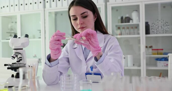 Female chemist wipes residue on tube with cotton stick for experiment. Lab providing essential resources needed for scientific research slow motion