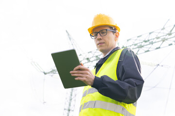Engineer with digital tablet on a background of power line tower.
